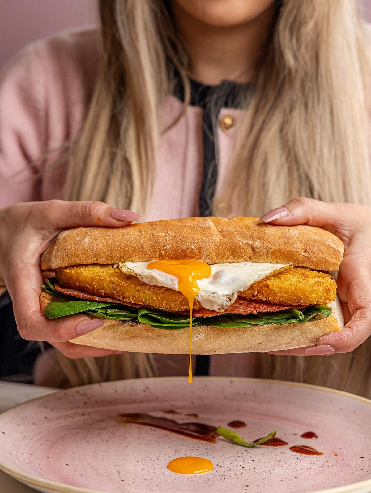 Brekkie roll with hash brown, fried egg, bacon and spinach on a toasted bun