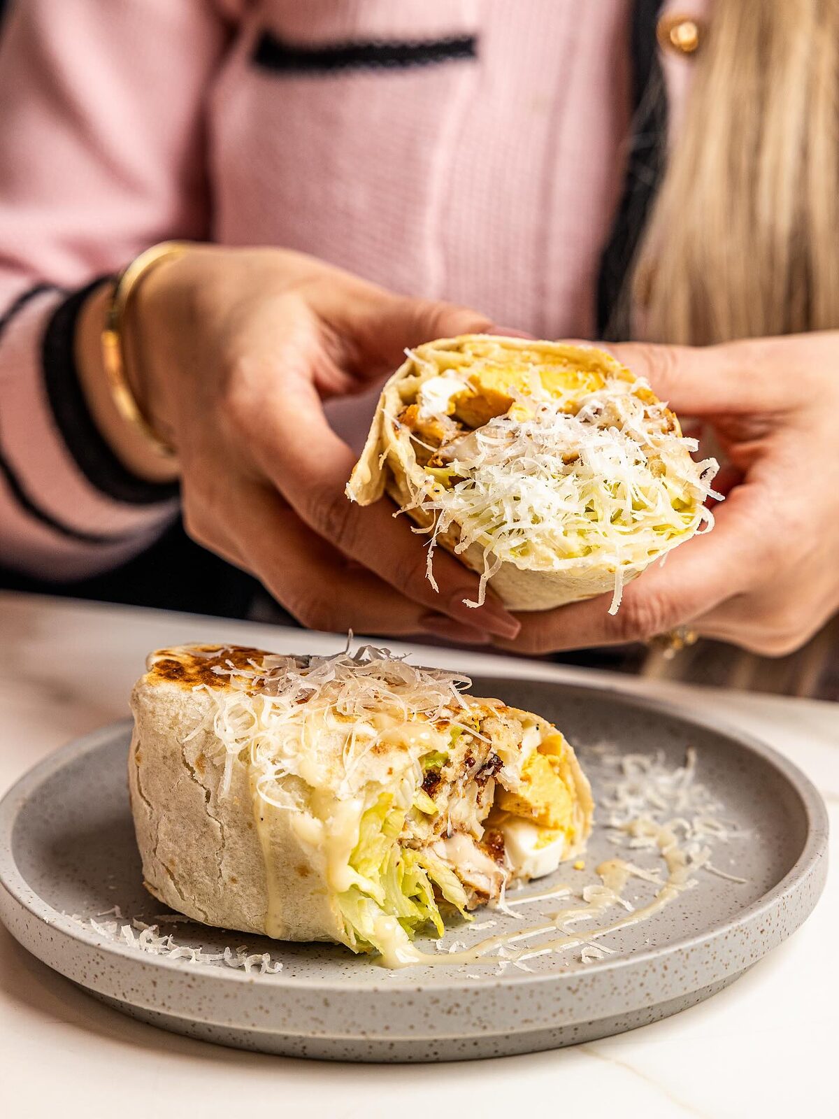 A caesar wrap cut in half, showing chicken, lettuce and parmesan