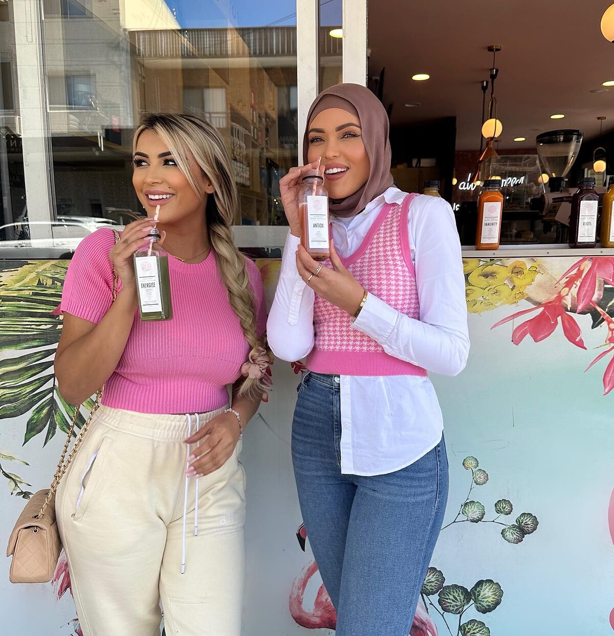 Two customers in pink sipping Soft Sip drinks outside the cafe