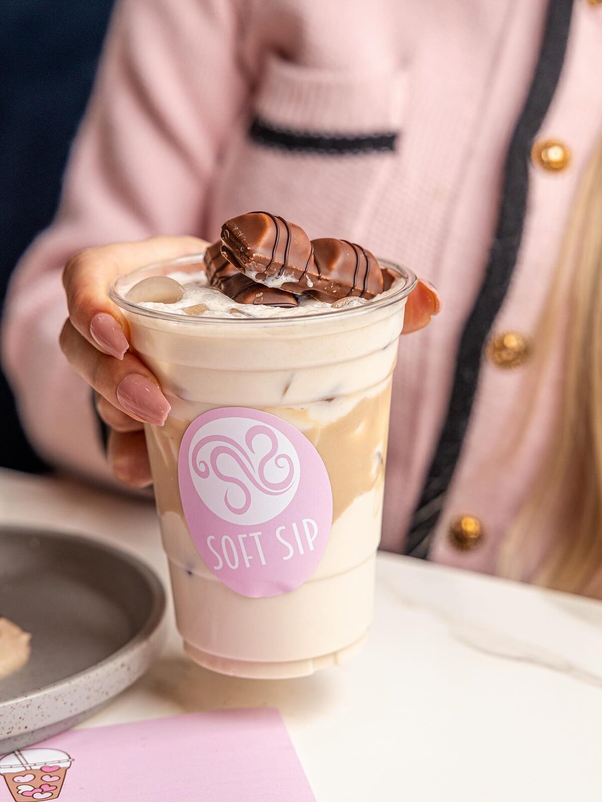 An iced Bueno latte topped with cream and a Kinder Bueno in a Soft Sip cup