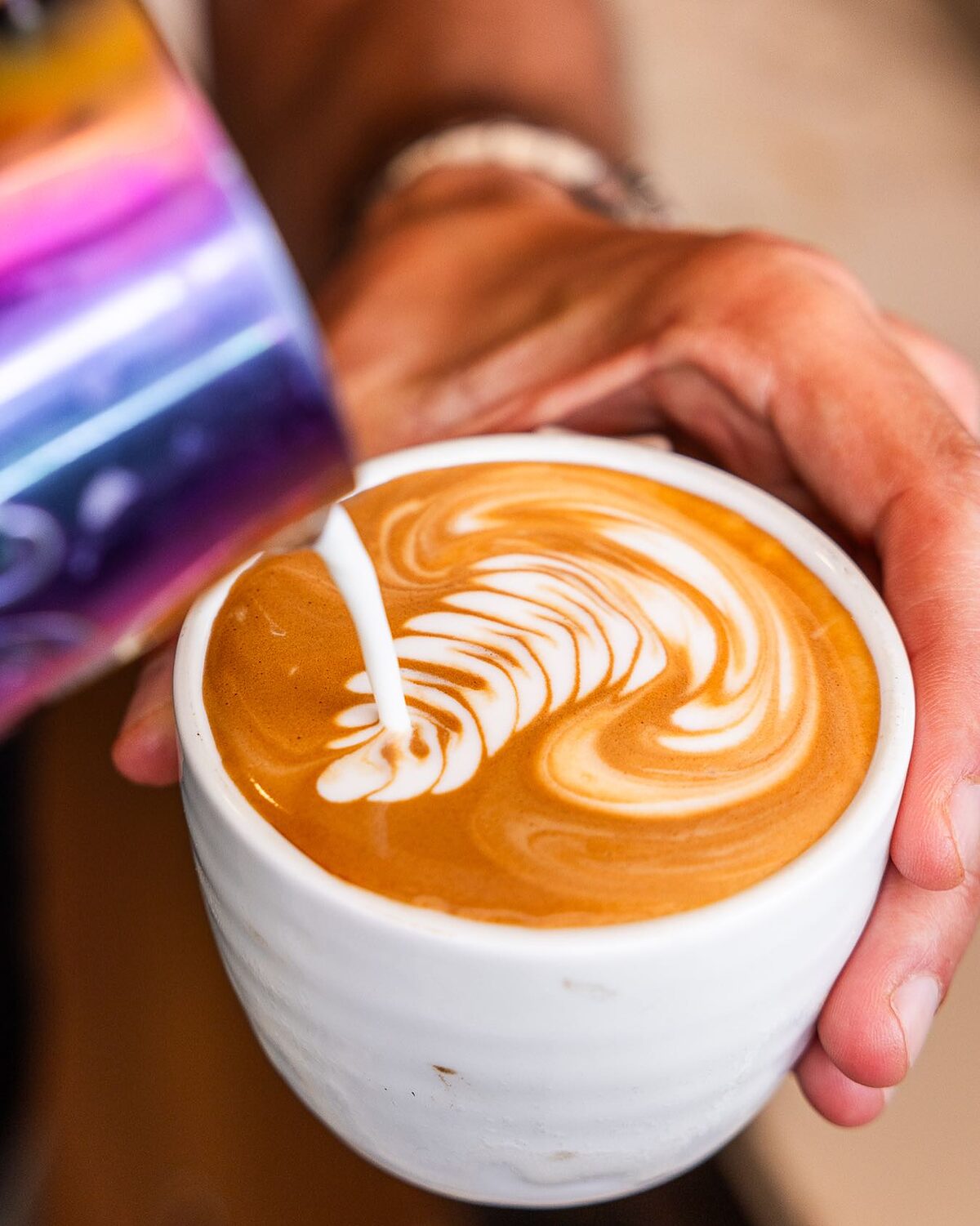 A barista pouring a rosetta into a flat white at Soft Sip