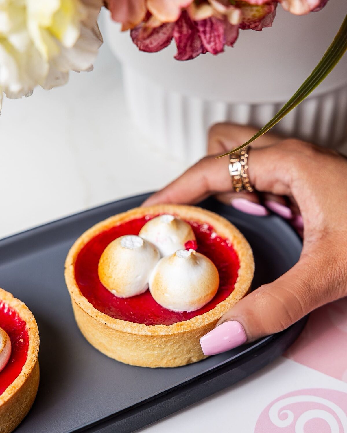 Lemon meringue tart with torched meringue peaks on a black tray at Soft Sip